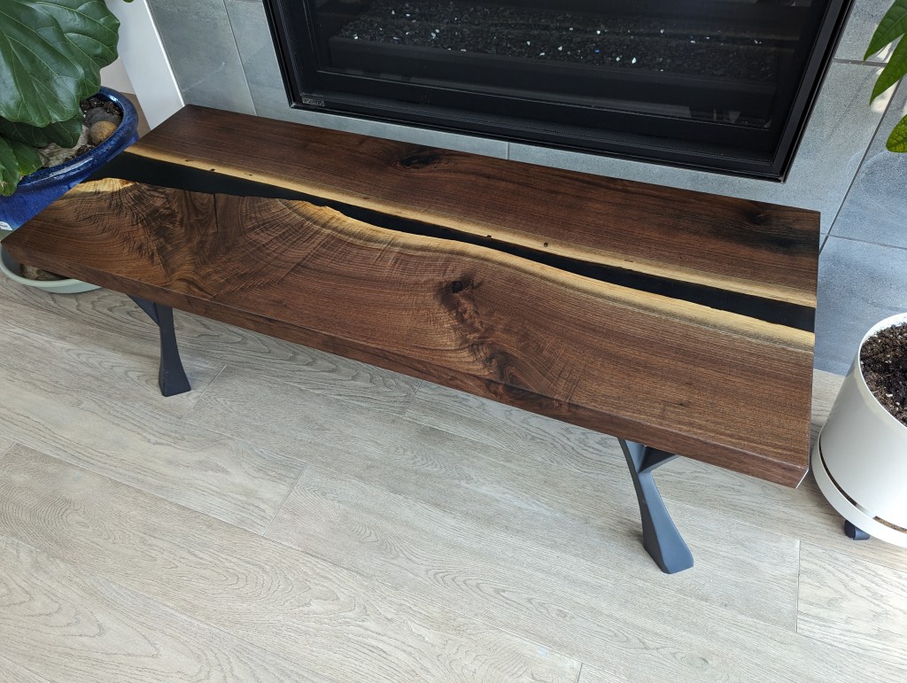 Handcrafted black walnut dining table with live-edge detail and modern polished steel legs, showcasing unique wood grain.