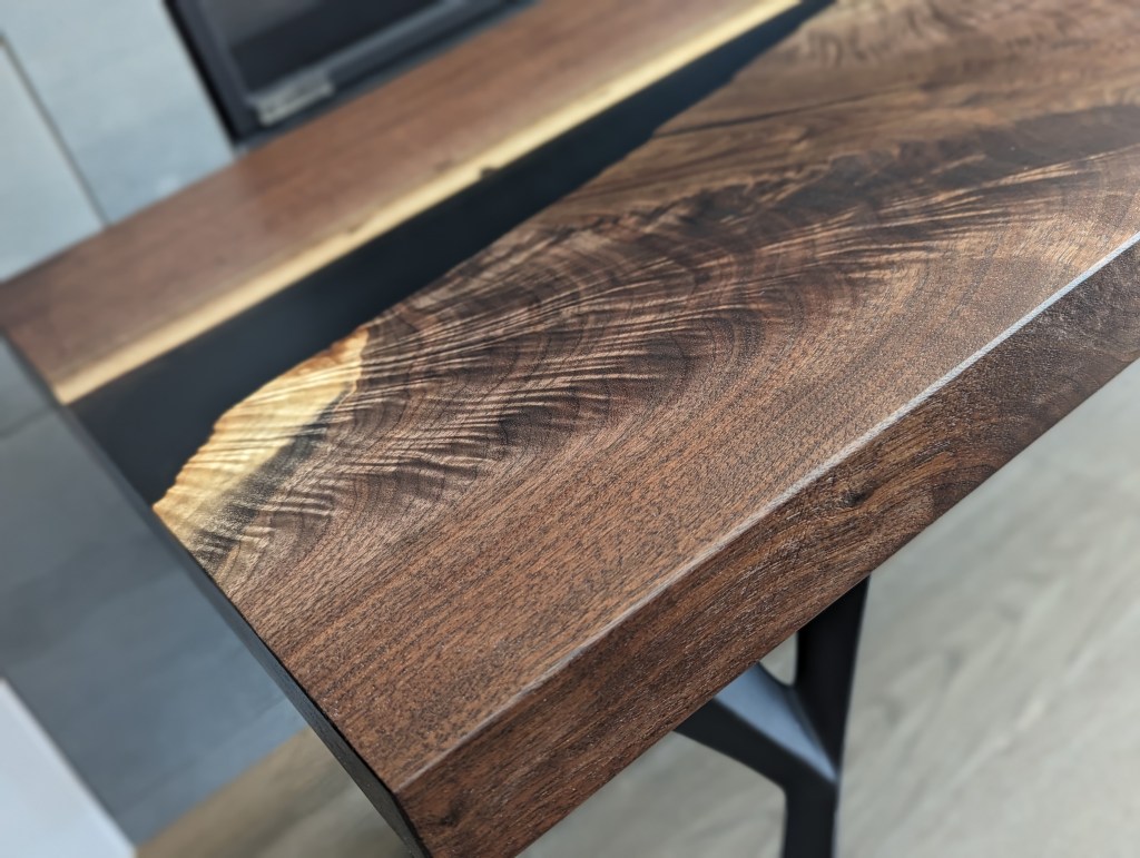 Close-up view of the live-edge black walnut dining table showcasing its rich wood grain and polished finish.