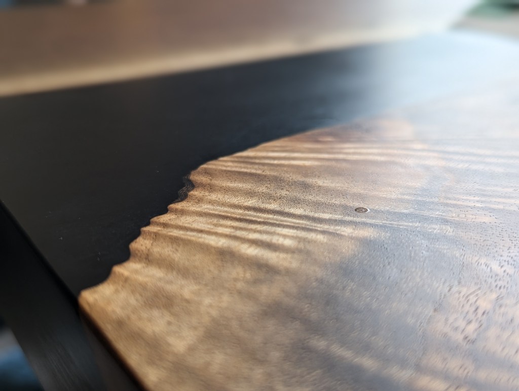 Close-up view of a handcrafted black walnut dining table showcasing its live-edge detail.