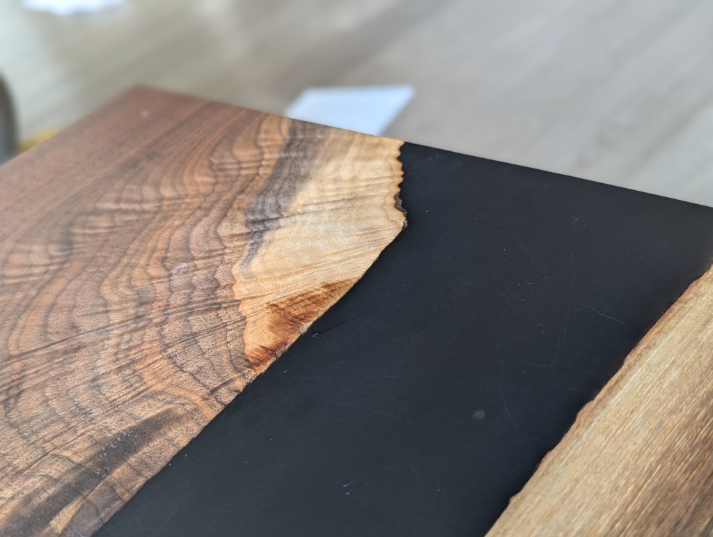 Close-up view of a handcrafted black walnut dining table showcasing the live-edge detail and polished surface.