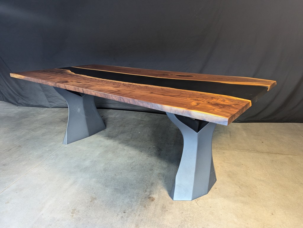 A handcrafted black walnut dining table featuring a live-edge top and modern steel legs, showcasing a unique grain pattern, designed to seat 6 to 8 guests.
