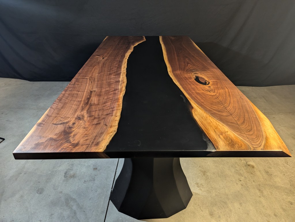Handcrafted black walnut dining table with a live-edge design and modern black steel legs, showcasing unique wood grain details.
