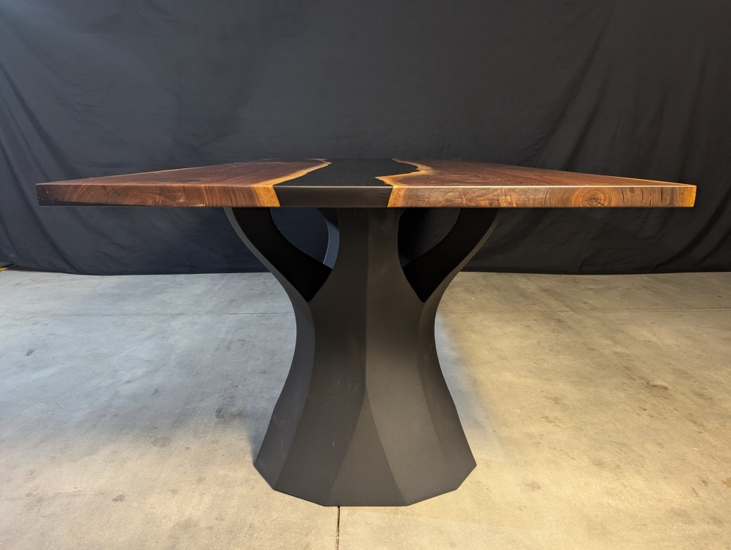 Handcrafted black walnut dining table with a live-edge detail and modern polished black steel legs, showcasing a unique design.