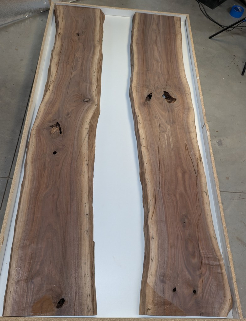 Two slabs of black walnut wood with live edges, showcasing natural grains and knots, on a white surface.  