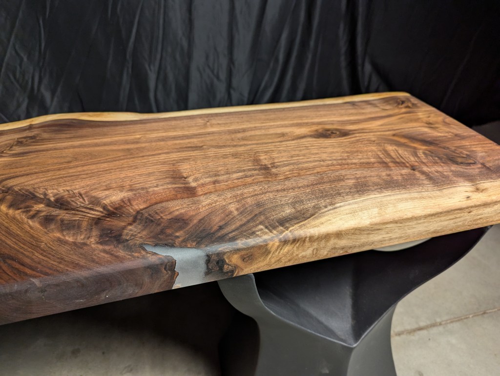 Close-up view of a wooden tabletop with a natural finish, showcasing intricate grain patterns and a smooth edge.