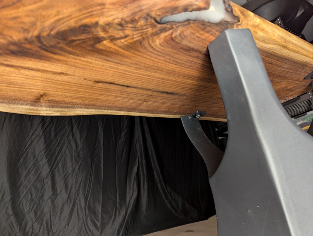 Close-up view of the underside of a wooden table showcasing its rich grain and a metal leg support.