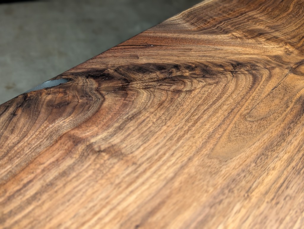 Close-up view of a wooden surface showcasing natural grain patterns and a small imperfection on the edge.