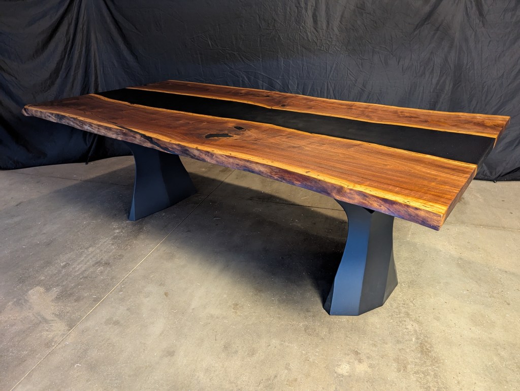 Handmade black walnut table with dyed black epoxy resin inlay, featuring live edges. The table is 90 inches long and has brushed steel legs.