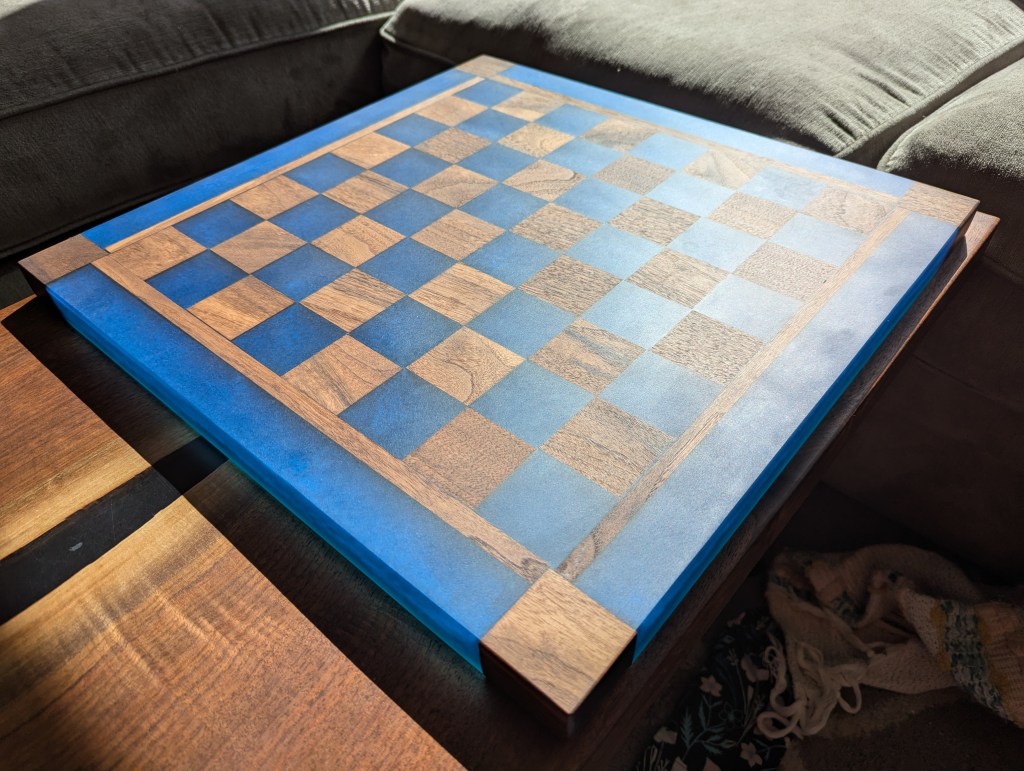 A custom chess board made from black walnut and dyed pacific blue epoxy resin, featuring 2" squares for tournament play.