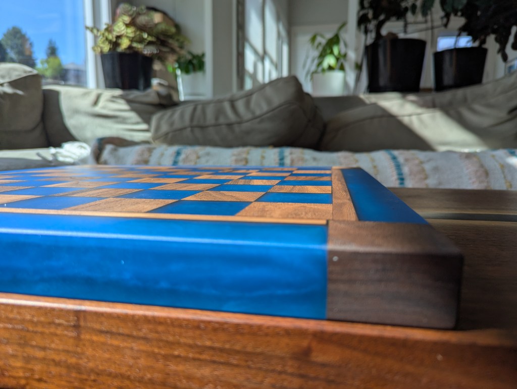 Custom chess board made from black walnut and dyed epoxy resin, featuring a blue color and traditional square layout.