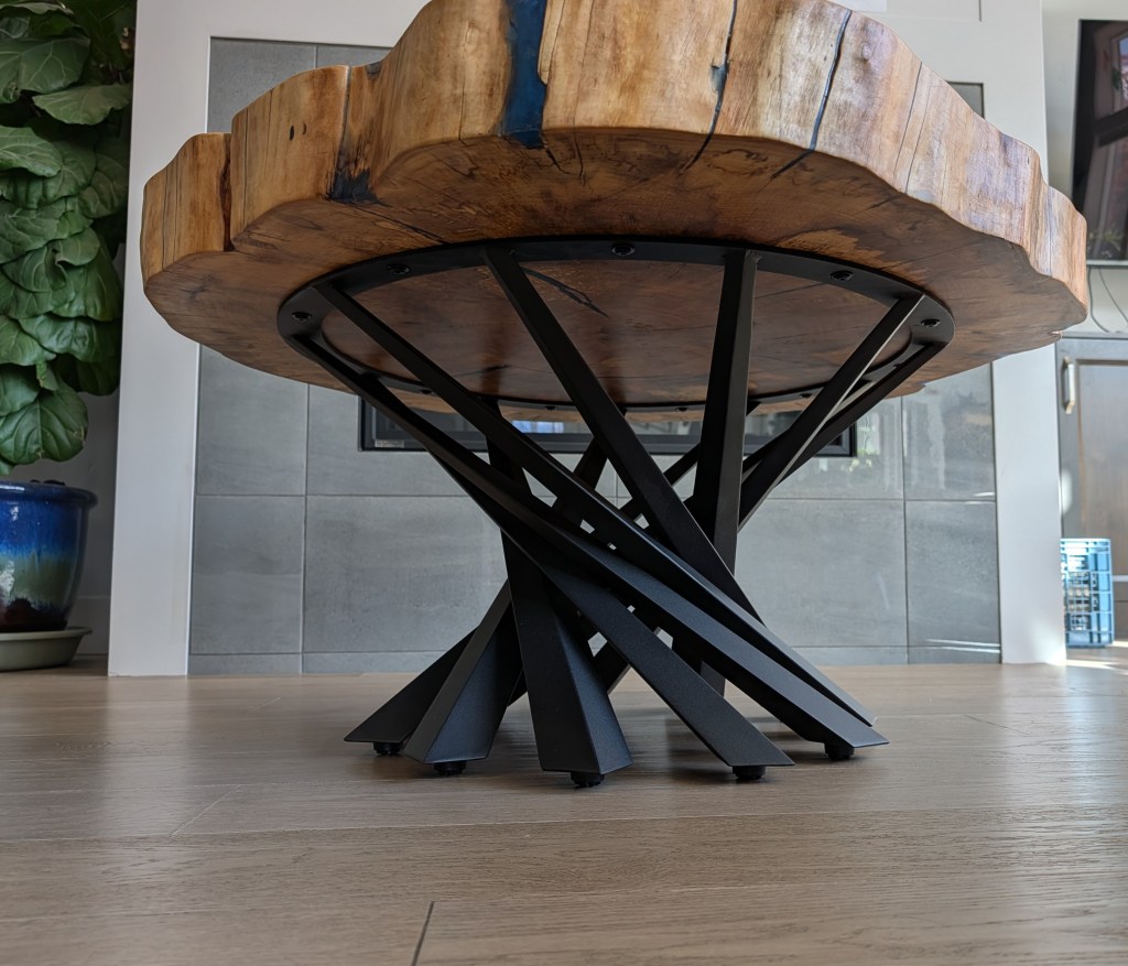 Underside view of handcrafted spalted cottonwood coffee table with sculptural black steel pedestal base.