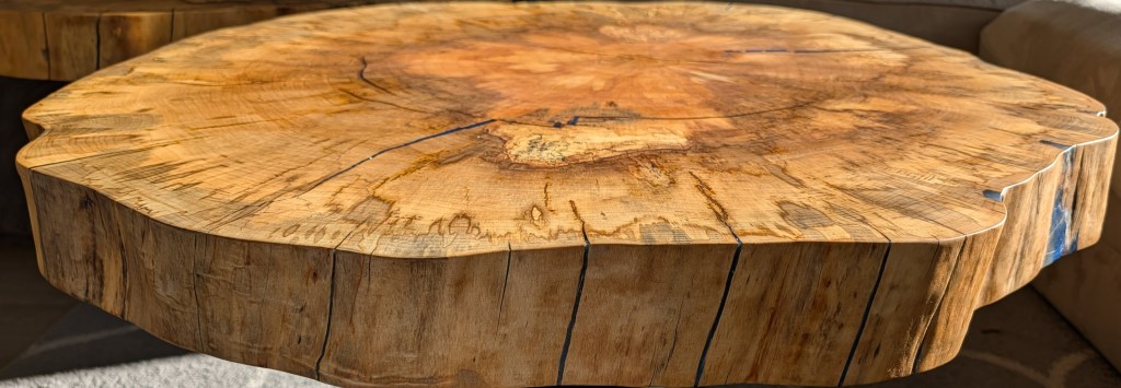 Low-angle view of handcrafted spalted cottonwood coffee table highlighting the live edge, natural grain, and blue epoxy accents.