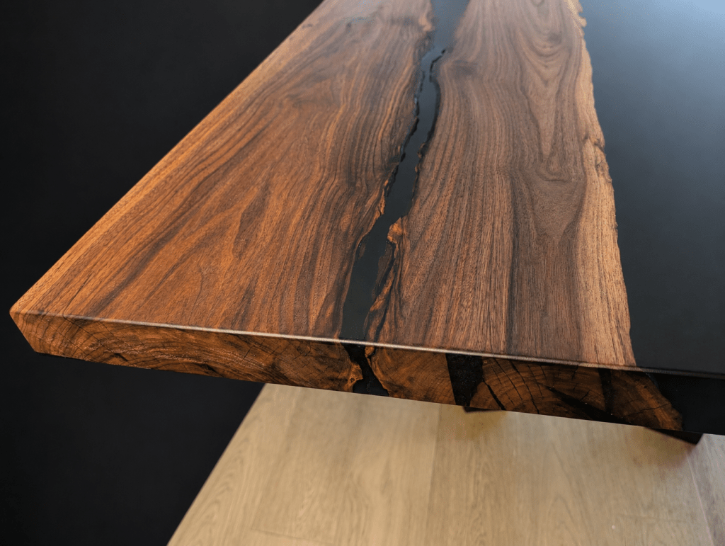 Close-up of the end of an adjacent-slab black walnut dining table showing the epoxy river.