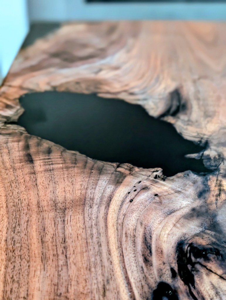 Close-up of the black epoxy river flowing through figured black walnut grain on a handcrafted river dining table.