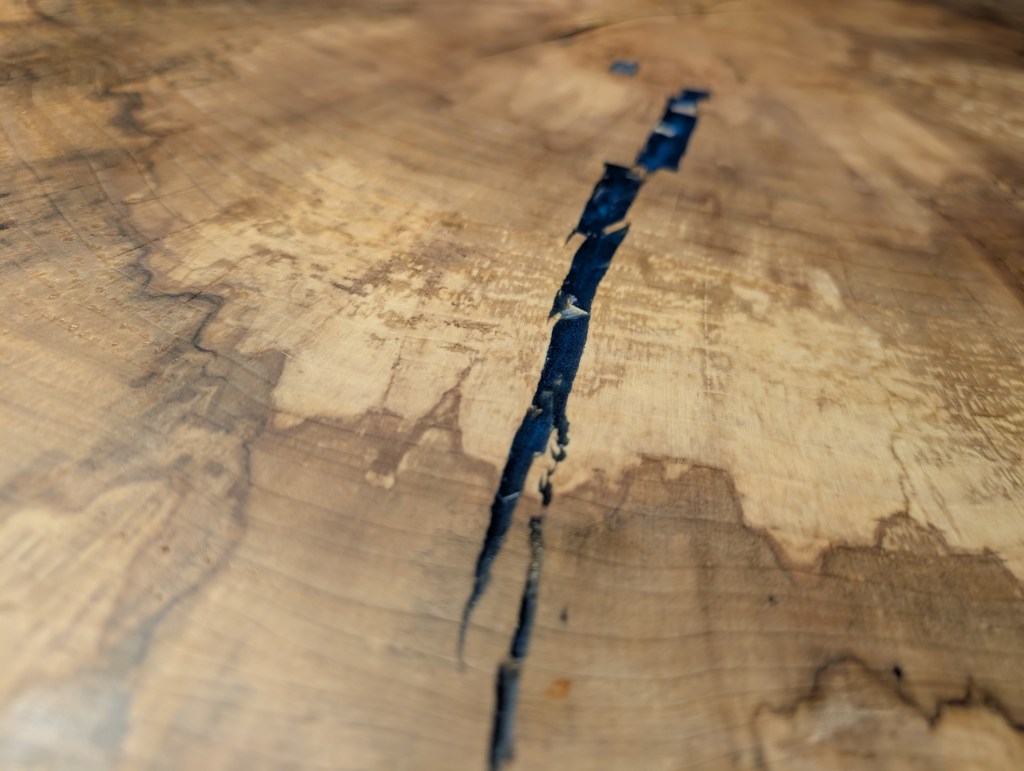 Close-up of natural crack stabilized with blue epoxy in a spalted cottonwood tabletop.